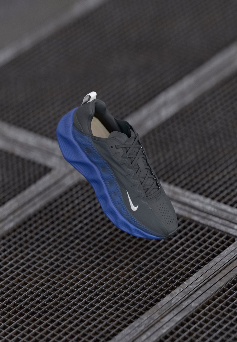 Nike αθλητικά παπούτσια με γκρίζο επάνω μέρος, μπλε σόλα και υφασμάτινες λεπτομέρειες. Περιλαμβάνουν μαύρα κορδόνια και λευκό λογότυπο στο πλάι.