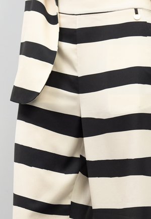 Traje de rayas negras y blancas con una textura de tela suave. Presenta rayas horizontales anchas, un corte entallado y un sutil detalle de herrajes plateados.