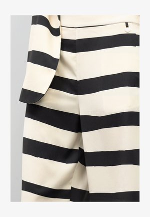 Traje de rayas negras y blancas con una textura de tela suave. Presenta rayas horizontales anchas, un corte entallado y un sutil detalle de herrajes plateados.