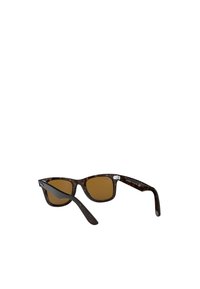 Occhiali da sole tartaruga con lenti marroni, design a occhio di gatto e montatura spessa. Presenta dettagli in argento sulle astine.