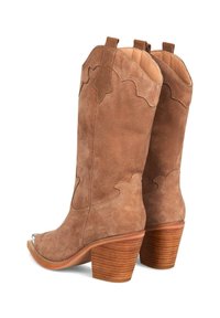 Stivali da cowboy in suede marrone con punta affusolata, dettagli intricati cuciti e tacco impilato. Presentano accenti curvi nella parte superiore.