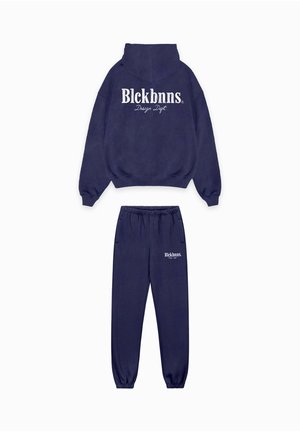 Marineblauwe fleece hoodie met kangoeroezak en wit logo op de achterkant; bijpassende sweatpants met elastische tailleband en logo op de linkerdij.
