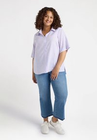 Camicia a righe viola chiaro e bianca con maniche corte, abbinata a jeans cropped blu chiaro e sneakers bianche.