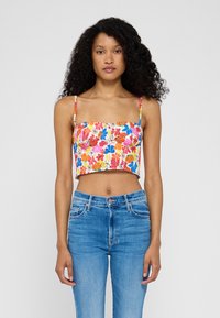 Top corto floreale con stampa multicolore, scollatura quadrata e spalline sottili. Abbinato a jeans a vita alta di colore blu chiaro.