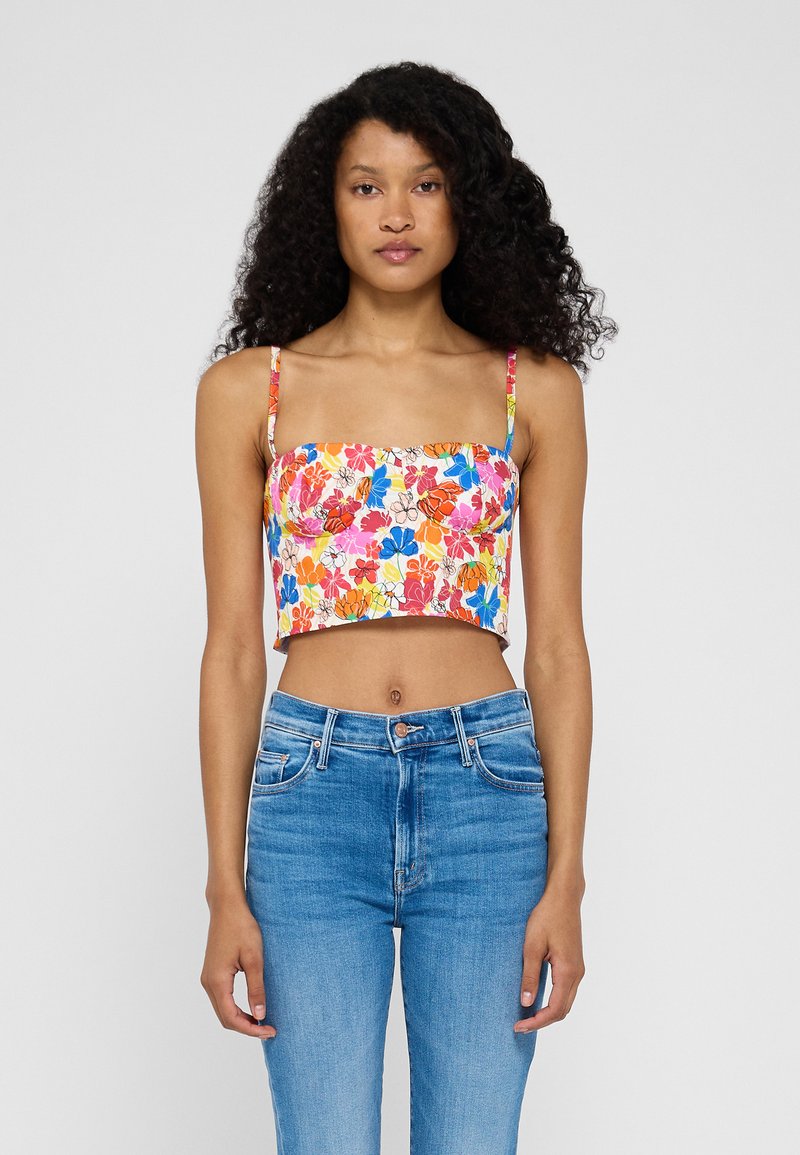 Top corto floreale con stampa multicolore, scollatura quadrata e spalline sottili. Abbinato a jeans a vita alta di colore blu chiaro.