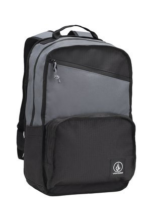 Mochila gris y negra hecha de un tejido duradero, que cuenta con múltiples compartimentos con cremallera, un asa superior y un parche con el logo en la parte frontal.