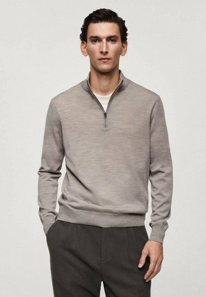 Pullover grigio con zip al collo, realizzato in tessuto morbido, caratterizzato da maniche lunghe e vita aderente. Indossato con pantaloni grigi scuri su misura.