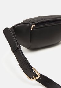 Zwarte lederen schoudertas met een gestructureerde vorm, gouden hardware, gequilt details en een verstelbare schouderband. Ritssluiting zichtbaar.