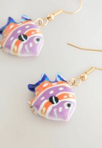 Bunte fischförmige Ohrringe aus Keramik mit lila, orange und schwarzen Mustern. Goldfarbene Metallhaken sorgen für einen Kontrast.