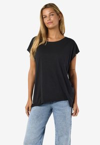 Tricou negru cu mânecă scurtă, croială lejeră, tiv curbat și textură moale; combinat cu blugi de culoare albastru deschis.