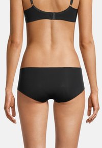 Schwarze nahtlose Hipster-Unterwäsche aus glattem Material und minimalistischem Design, mit einem tiefen Schnitt und sauberen Kanten.