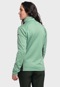 Hellgrüne Fleecejacke mit hohem Kragen, Reißverschluss und Einsatzpaneelen. Verfügt über strukturierten Stoff und dezente Stickdetails.