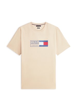 Béžové tričko s krátkym rukávom a okrúhlym výstrihom, so štvorcovým logom Tommy Hilfiger v modrej, bielej a červenej farbe v strede na hrudi.