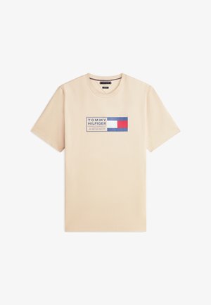 Béžové tričko s krátkym rukávom a okrúhlym výstrihom, so štvorcovým logom Tommy Hilfiger v modrej, bielej a červenej farbe v strede na hrudi.