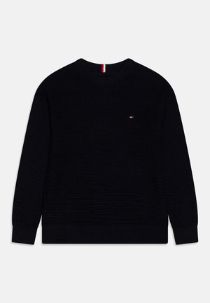 Maglione nero a maglia con scollo rotondo, polsini e orlo a costine. Piccolo logo rosso, bianco e blu sul lato sinistro del petto. Superficie testurizzata.