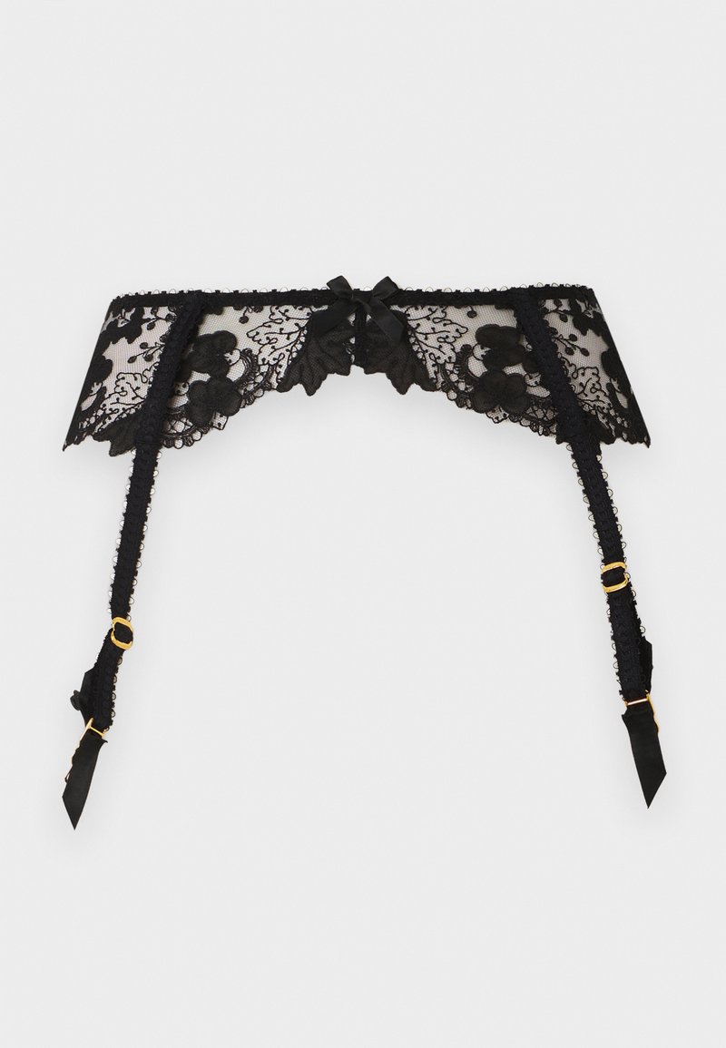 Jarretière en dentelle noire avec motifs floraux, petit nœud central, et attaches réglables en métal doré sur les bretelles.