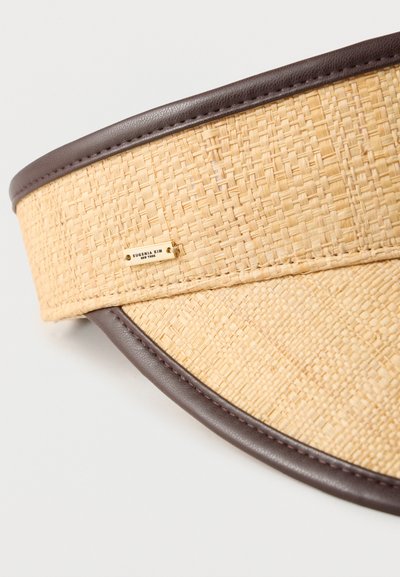 Πλεκτή ψάθινη ζελατίνα με καφέ δερμάτινη ταινία. Φέρει μια χρυσή πινακίδα λογότυπου με την επιγραφή "Eugenia Kim New York." Στρογγυλεμένο, δομημένο σχέδιο.