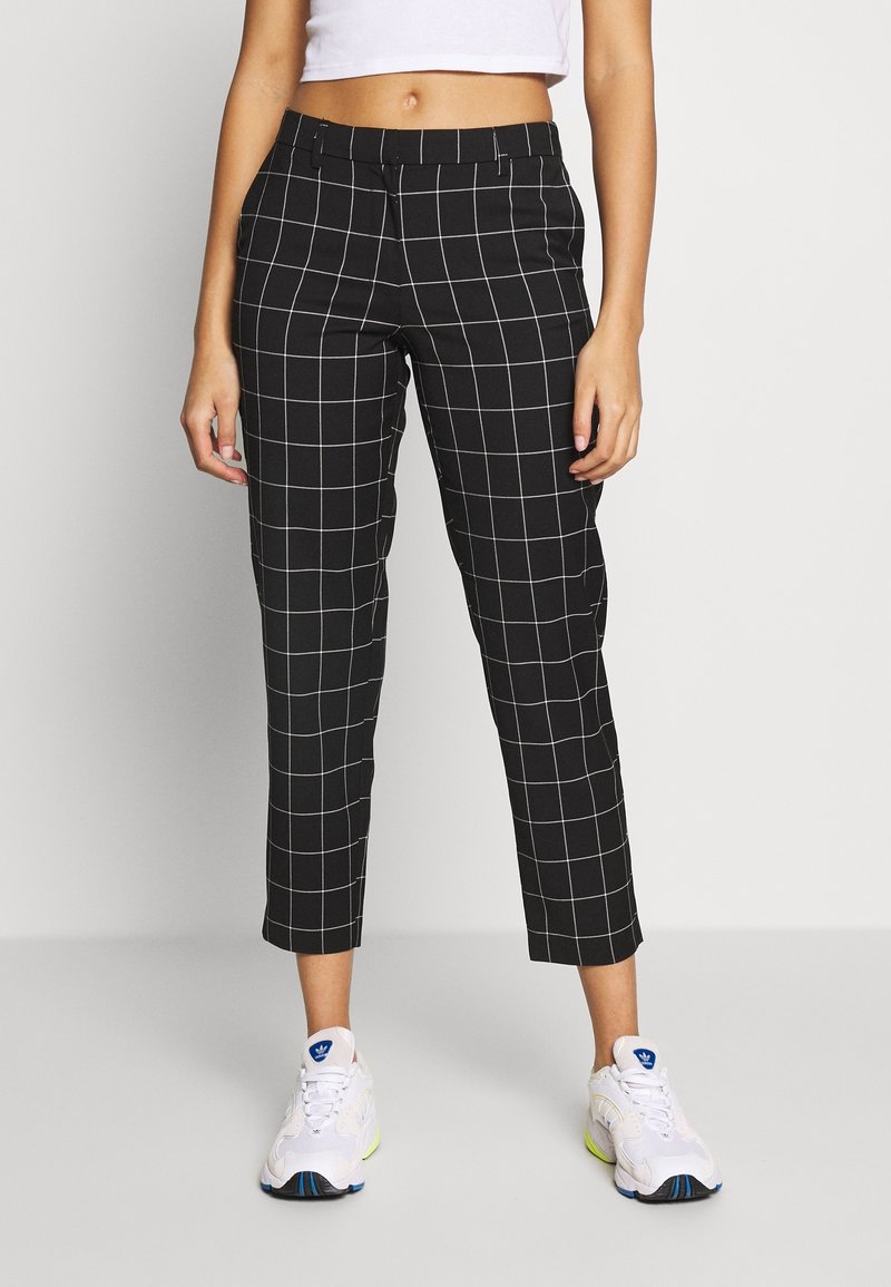 Pantalon à carreaux noirs en tissu lisse; coupe fuselée avec taille mi-haute et longueur cheville, avec des lignes de grille blanches.