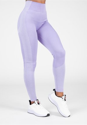 High-waisted lavender leggings with textured side panels, made from stretchy material, paired with white athletic shoes.