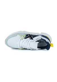 Zapatilla deportiva blanca con detalles de malla, acentos negros y superposiciones en verde neón. Presenta una lengüeta acolchada, cordones blancos y una pestaña en el talón amarilla.