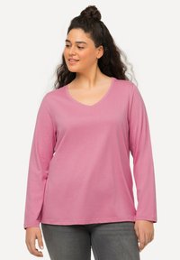 Light pink long-sleeve shirt with a V-neck design, made from soft material, featuring a relaxed fit and simple stitching details.