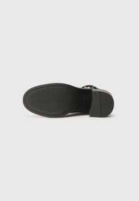 Suola nera di scarpa con un motivo testurizzato, design piatto e finitura liscia. Caratterizzata da una costruzione robusta e dettagli minimali.