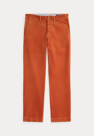 Pantalon en velours côtelé couleur rouille avec poches avant, passants de ceinture et fermeture par bouton, posé à plat sur un fond clair.