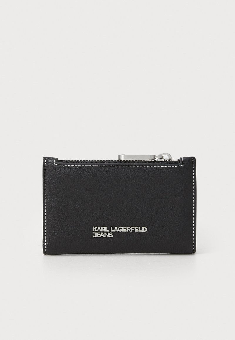 Svart läderplånbok med vit söm och dragkedja. Har en silverlogotyp "KARL LAGERFELD JEANS" på framsidan. Kompakt design.