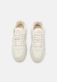 White leather sneakers featuring tonal stitching, perforated toe cap, and flat laces. The design includes a subtle accent on the tongue.