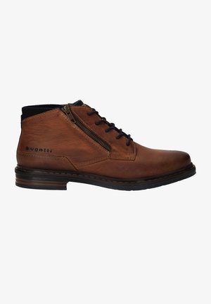 Braune Lederstiefeletten mit runder Zehenpartie, marineblauen Akzenten, seitlichem Reißverschluss und strukturiertem Obermaterial. Flache Gummisohle mit kontrastierenden Nähten.