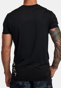 Černé aktivní tričko z lehké tkaniny, s krátkými rukávy a zakulaceným spodním lemem. Na spodní části bíle tištěné logo "RVCA".