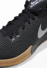 Nærbillede af sorte Nike Zoom Live sneakers med struktureret mesh-stof, sorte snørebånd, hvid Nike swoosh og gummi sål med Zoom branding.