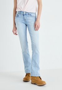Light blue denim jeans with a straight cut, featuring five pockets and a button closure, paired with tan ankle boots.