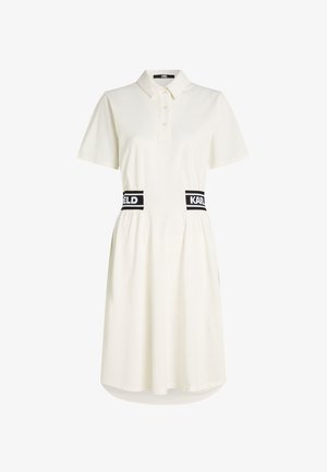 Robe polo blanche à manches courtes avec col, patte de boutonnage et ceinture élastique noire avec les inscriptions "KARL" et "FELD".