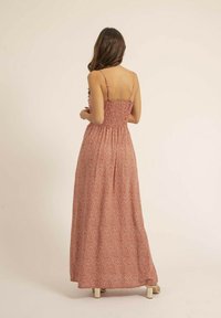 Robe maxi au motif floral rouge et blanc, dotée d'un corsage smocké, de bretelles spaghetti réglables et d'une silhouette fluide avec une texture douce.