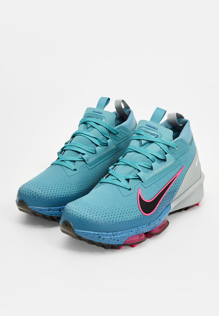 Turkusowe buty biegowe z nakrapianą niebiesko-różową podeszwą, teksturowanym materiałem cholewki, czarnym logo Swoosh i szarymi akcentami na pięcie.