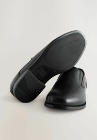 Zapatos de cuero negros con un acabado suave, puntera redondeada y diseño de fácil colocación. Suela de goma texturizada con un patrón de diamantes para mayor agarre.