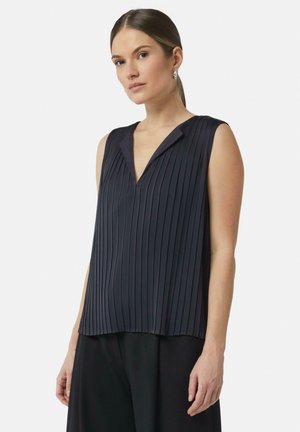 Marineblaue ärmellose Bluse mit vertikalen Falten, V-Ausschnitt, weicher Textur und lockerer Passform. Kombiniert mit schwarzen Hosen, minimalistisches Design.