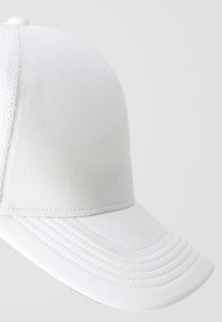 Casquette de baseball blanche avec une couronne lisse, une visière texturée et des détails de couture. Les panneaux latéraux en mesh améliorent la respirabilité.