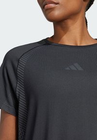 Maglietta sportiva nera con un design testurizzato, dotata di maniche corte, scollatura rotonda e un branding discreto sul davanti.