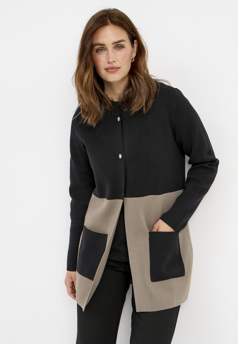 Schwarze und beige Strickjacke mit Knopfverschluss, langen Ärmeln und zwei Vordertaschen. Strukturierter Stoff mit einem Farbblock-Design.