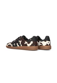 Sneaker a stampa di mucca che presenta un mix di materiale simile alla pelliccia bianca e nera, dettagli neri e una suola in gomma. Design classico a bassa altezza.