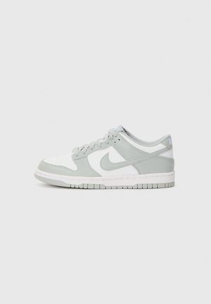 Nike Dunk Low sporta apavi ar baltu ādas pamatni, gaiši pelēkiem zamšādas akcentiem, pildītu apkakli un gumijas zoli.