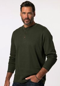 Donkergroene henley shirt met lange mouwen en een geribbelde textuur, voorzien van een ronde halslijn, een knoopsluiting met drie bruine knopen en aansluitende manchetten.