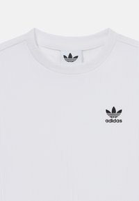 Biela pruhovaná tričko s krátkym rukávom, okrúhlym výstrihom a čiernym logom Adidas na ľavom prsníku. Mäkká tkanina s jemnou štruktúrou.