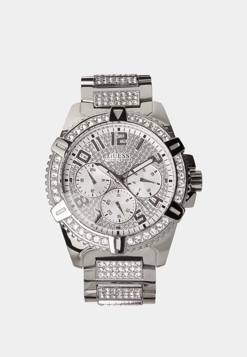 Montre-bracelet Guess argent avec cadran, lunette et bracelet ornés de cristaux, comprenant trois sous-cadrans et des index noirs et argentés.