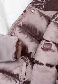 Gevoerde jas in glanzend mauve stof met een doorgestikt ontwerp, voorzien van een rits en ribgebreide manchetten, evenals een merketiket op de mouw.