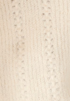 Zacht crèmekleurig gebreid stof met verhoogde, gestructureerde patronen en een pluizig oppervlak, met gedetailleerde steken die verfijnd vakmanschap tonen.