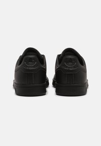 Sorte lædersneakers med teksturerede paneler, gummisåler og præget branding på hælen. Minimalistisk design med en low-top silhuet.