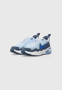 Plave i tamnoplave sportske tenisice s mrežastim materijalom, bijelim vezicama i plavim Nike logom. Imaju podstavljeni đon i kontrastne akcentne boje.